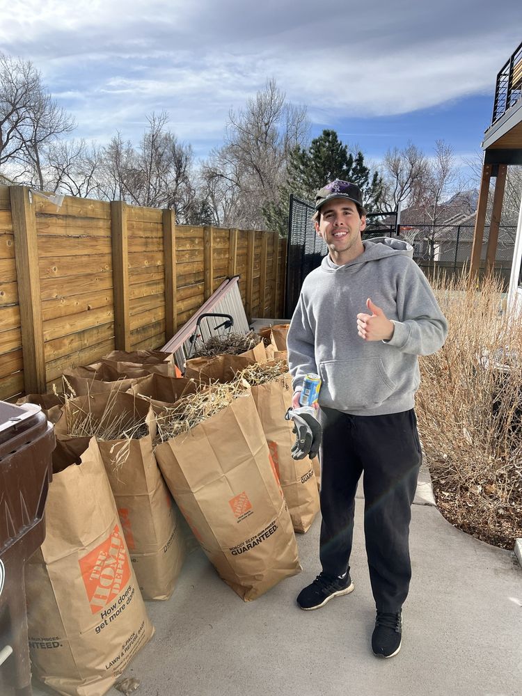 A Joe's worker standing beside a row of full yard waste bags.